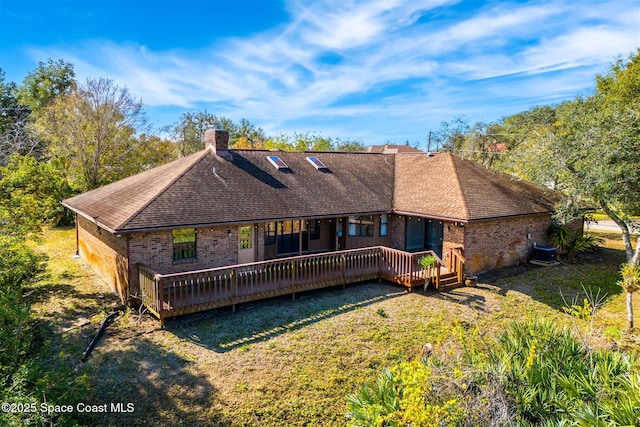 back of property with a wooden deck, a yard, and cooling unit