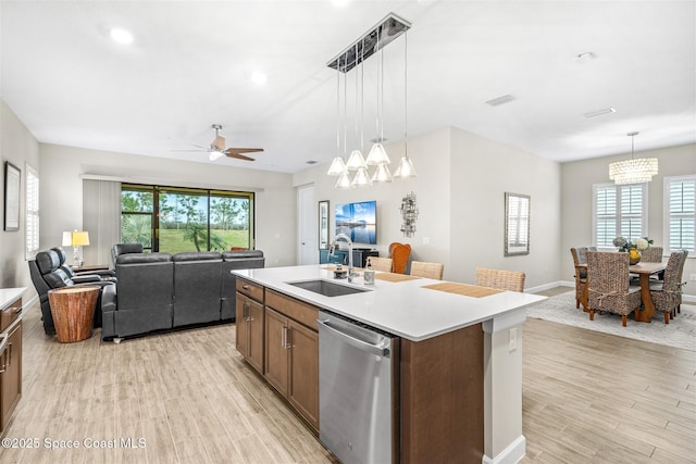 kitchen with pendant lighting, sink, an island with sink, ceiling fan with notable chandelier, and stainless steel dishwasher