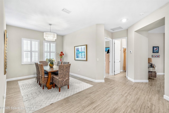 dining space featuring a notable chandelier and light wood-type flooring