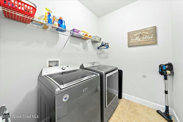 clothes washing area featuring light tile patterned floors and washer and dryer