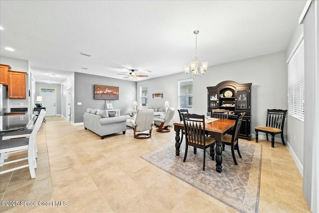 tiled dining space with ceiling fan with notable chandelier and a textured ceiling