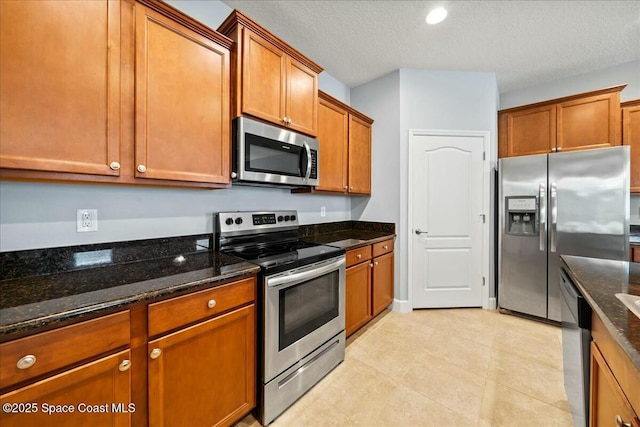 kitchen with dark stone countertops, a textured ceiling, and appliances with stainless steel finishes