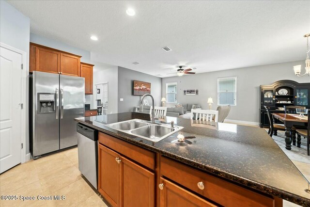 kitchen featuring sink, decorative light fixtures, a textured ceiling, dark stone countertops, and stainless steel appliances