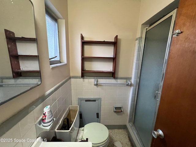 bathroom with tile walls, a shower with shower door, and toilet