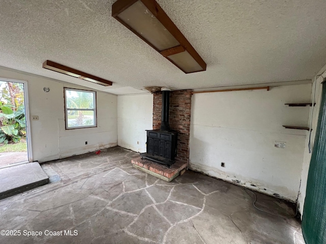 unfurnished living room featuring a textured ceiling and a wood stove