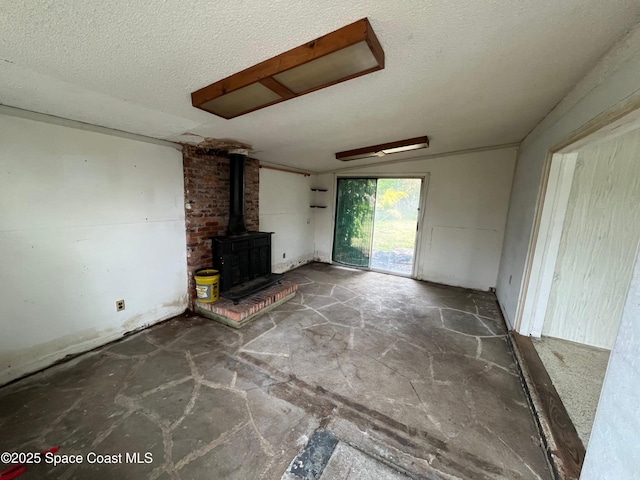 unfurnished living room featuring a wood stove and a textured ceiling