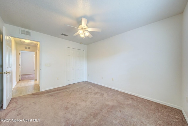 unfurnished bedroom featuring light carpet, a closet, and ceiling fan