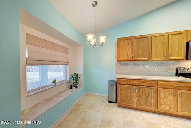 kitchen with appliances with stainless steel finishes, pendant lighting, lofted ceiling, backsplash, and light tile patterned floors