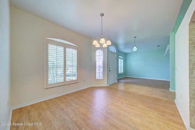 empty room featuring an inviting chandelier and light hardwood / wood-style flooring