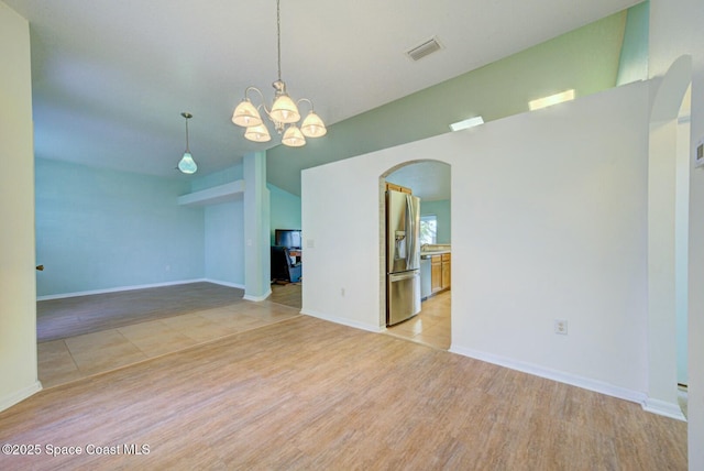 unfurnished room with an inviting chandelier, vaulted ceiling, and light wood-type flooring