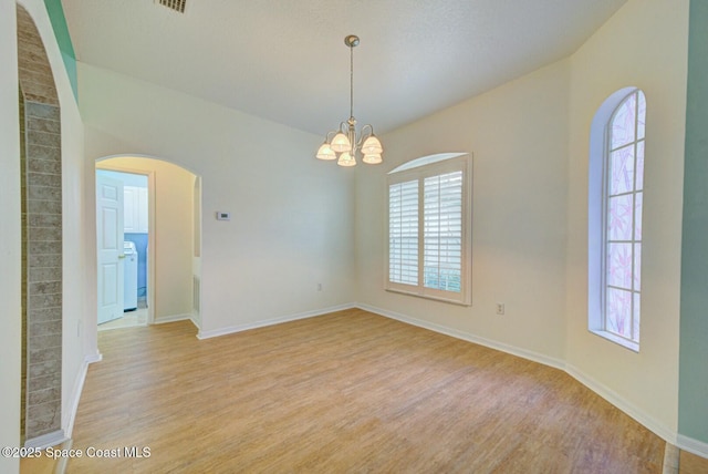 empty room featuring light hardwood / wood-style flooring and a chandelier