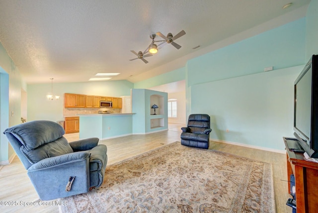 living room featuring lofted ceiling, ceiling fan with notable chandelier, a textured ceiling, and light hardwood / wood-style flooring