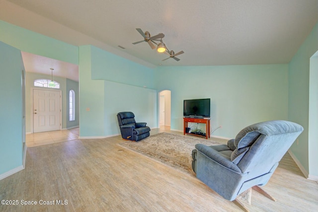 living room featuring ceiling fan, lofted ceiling, a textured ceiling, and light wood-type flooring