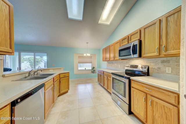 kitchen with lofted ceiling, sink, appliances with stainless steel finishes, backsplash, and decorative light fixtures