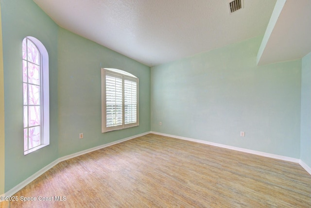 unfurnished room featuring light hardwood / wood-style flooring and a textured ceiling