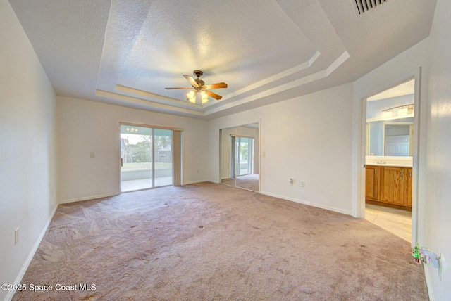 carpeted empty room featuring ceiling fan, a tray ceiling, sink, and a textured ceiling