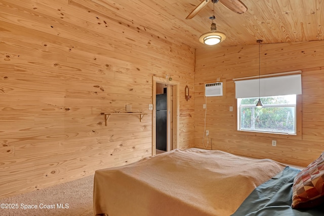 carpeted bedroom with wood ceiling, ceiling fan, a wall mounted AC, black fridge, and wood walls