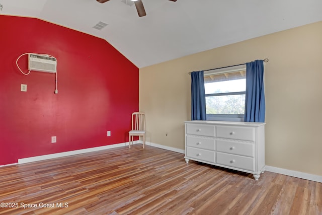 unfurnished room with lofted ceiling, an AC wall unit, ceiling fan, and light wood-type flooring