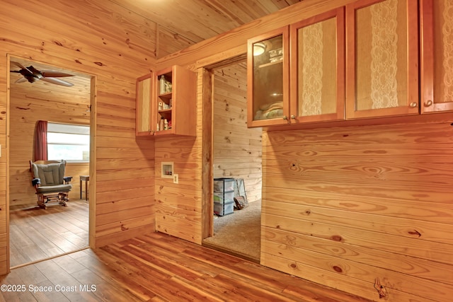 kitchen with wood ceiling, wooden walls, ceiling fan, and light wood-type flooring