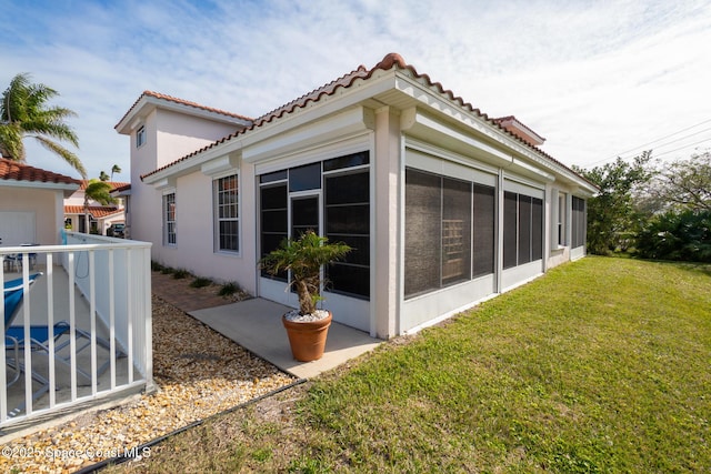 view of home's exterior with a sunroom and a yard