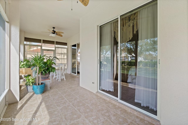 unfurnished sunroom featuring ceiling fan