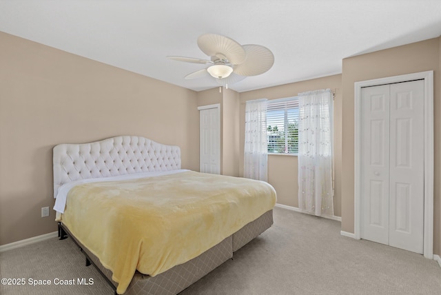 bedroom featuring multiple closets, ceiling fan, and light carpet