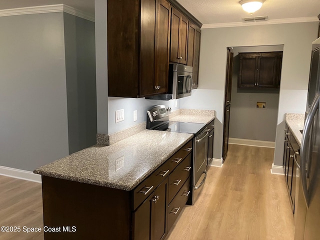 kitchen featuring appliances with stainless steel finishes, dark stone counters, dark brown cabinetry, and light hardwood / wood-style flooring