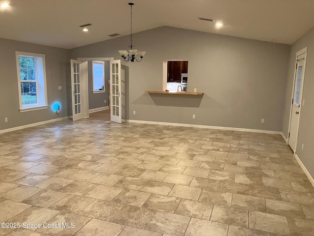 unfurnished living room with lofted ceiling, sink, and an inviting chandelier