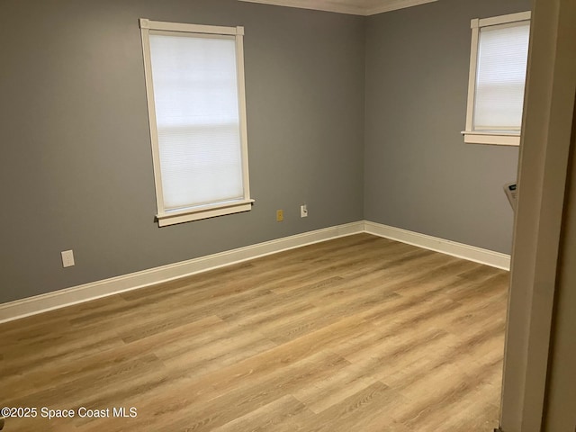 empty room with crown molding and light hardwood / wood-style flooring