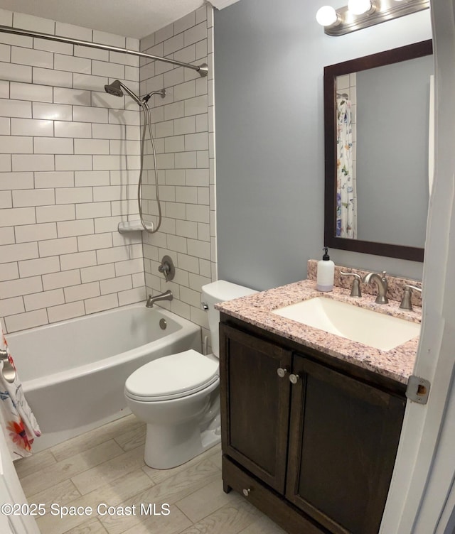 full bathroom with vanity, tiled shower / bath, and toilet