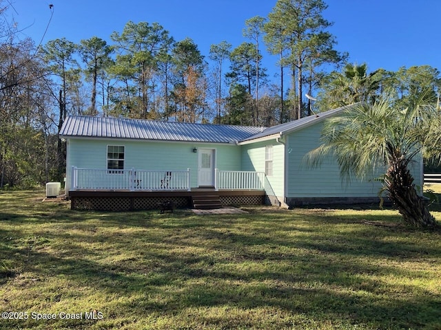 rear view of property featuring a wooden deck and a lawn