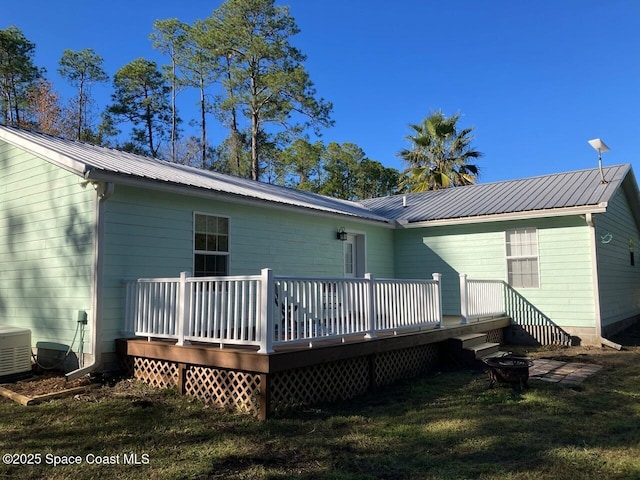 rear view of property with central AC unit, a lawn, and a deck