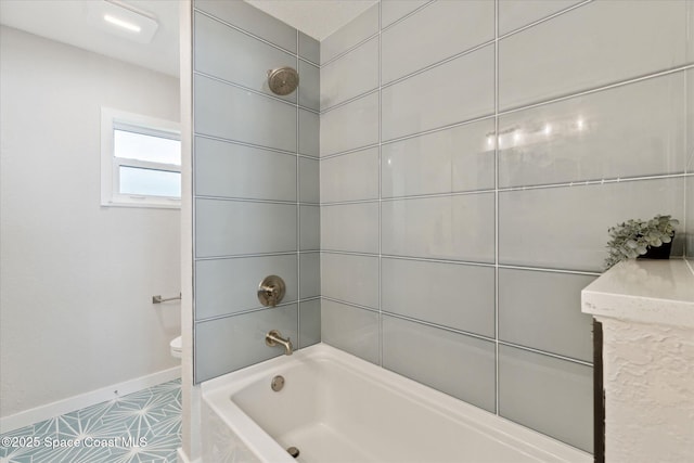 bathroom featuring tile patterned flooring, tiled shower / bath, and toilet