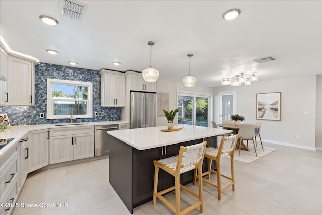 kitchen with a kitchen bar, sink, decorative light fixtures, a kitchen island, and stainless steel appliances