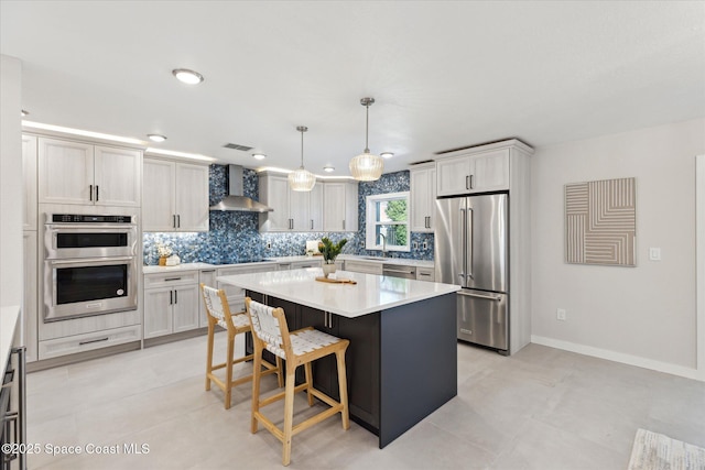 kitchen with sink, hanging light fixtures, a center island, stainless steel appliances, and wall chimney range hood