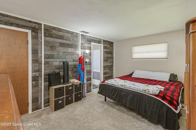 carpeted bedroom featuring wood walls