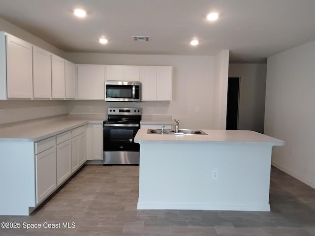 kitchen with sink, stainless steel appliances, white cabinets, and a center island with sink