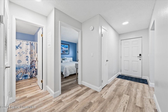 hallway with a textured ceiling and light wood-type flooring