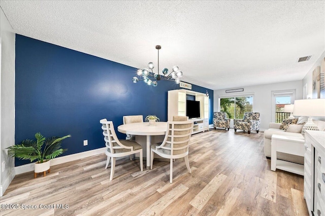 dining room featuring hardwood / wood-style floors, a textured ceiling, and an inviting chandelier