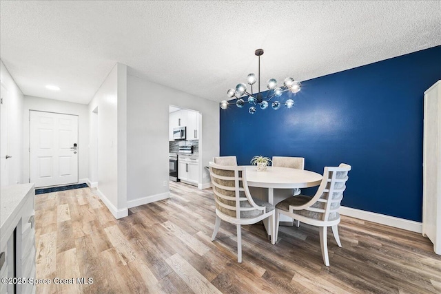 dining room featuring light hardwood / wood-style floors, a chandelier, and a textured ceiling