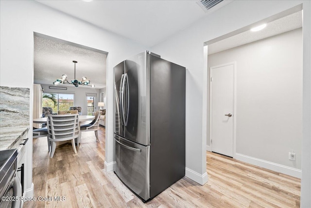 kitchen with pendant lighting, stainless steel fridge, a textured ceiling, and light hardwood / wood-style flooring