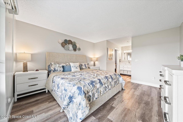 bedroom featuring connected bathroom, hardwood / wood-style floors, and a textured ceiling