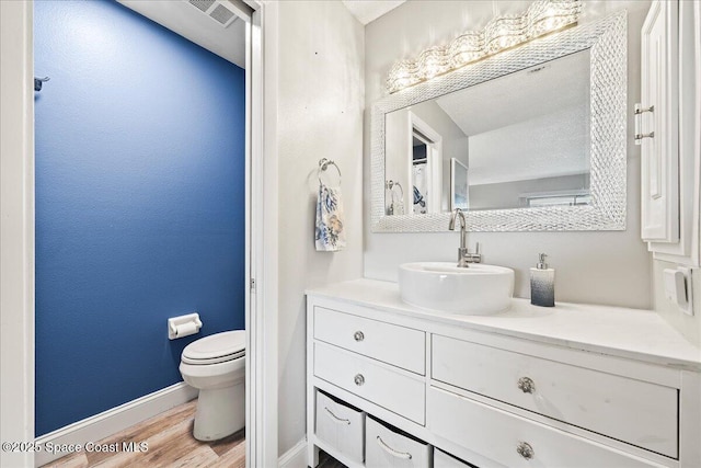 bathroom featuring vanity, hardwood / wood-style floors, and toilet