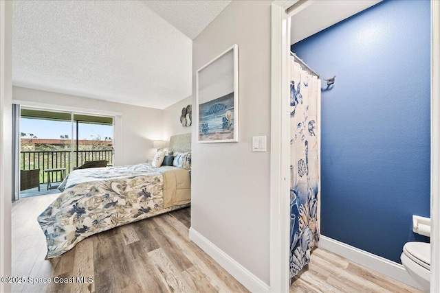 bedroom with access to outside, light hardwood / wood-style floors, and a textured ceiling