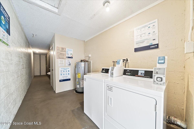 laundry area with a textured ceiling, water heater, and washing machine and clothes dryer