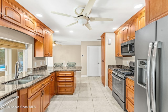 kitchen featuring appliances with stainless steel finishes, kitchen peninsula, sink, and dark stone countertops