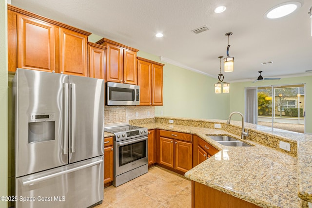 kitchen featuring stainless steel appliances, sink, decorative light fixtures, and kitchen peninsula