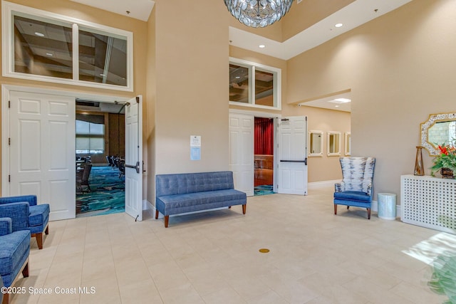 living area featuring an inviting chandelier, light tile patterned flooring, and a high ceiling