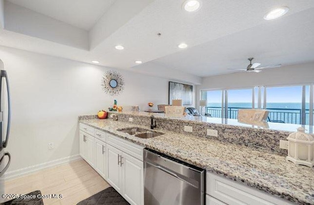 kitchen featuring sink, dishwasher, a water view, light stone countertops, and white cabinets