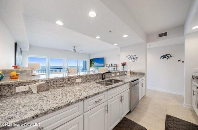 kitchen with sink, light stone counters, dishwasher, ceiling fan, and white cabinets